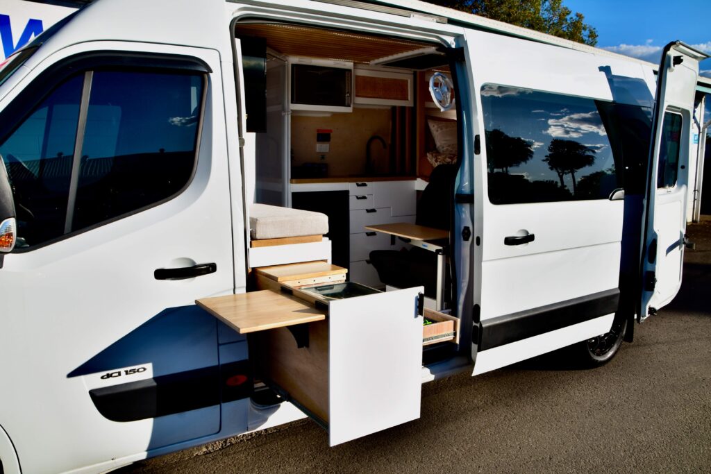 Revanped professional campervan fitout on the Sunshine Coast for Iveco Daily, featuring a large pull-out kitchen drawer storage box at the side sliding door, custom-built couch area, and upholstered cushions — specialists in bespoke camper van conversions, fabrication, and accessories.
