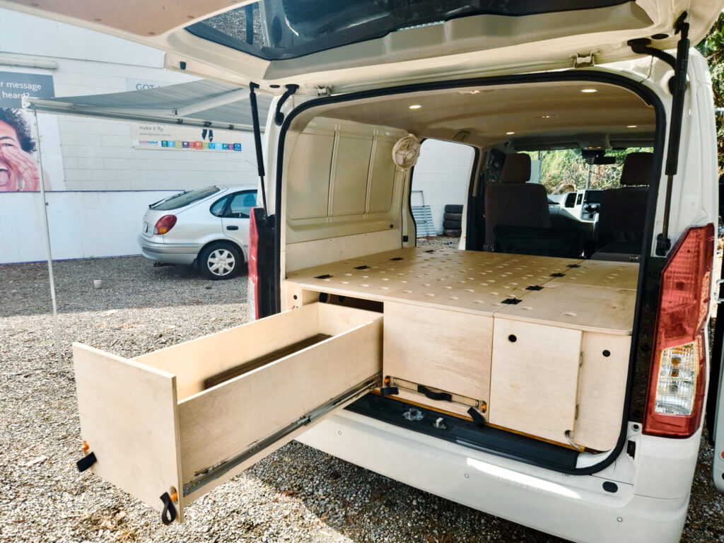 Revanped custom fabrication and cabinetry camper van fitout for Toyota Hiace on the Sunshine Coast, featuring a full-size rear bed area with ventilation holes to prevent moisture and mildew buildup — specialists in camper van conversions and accessories.